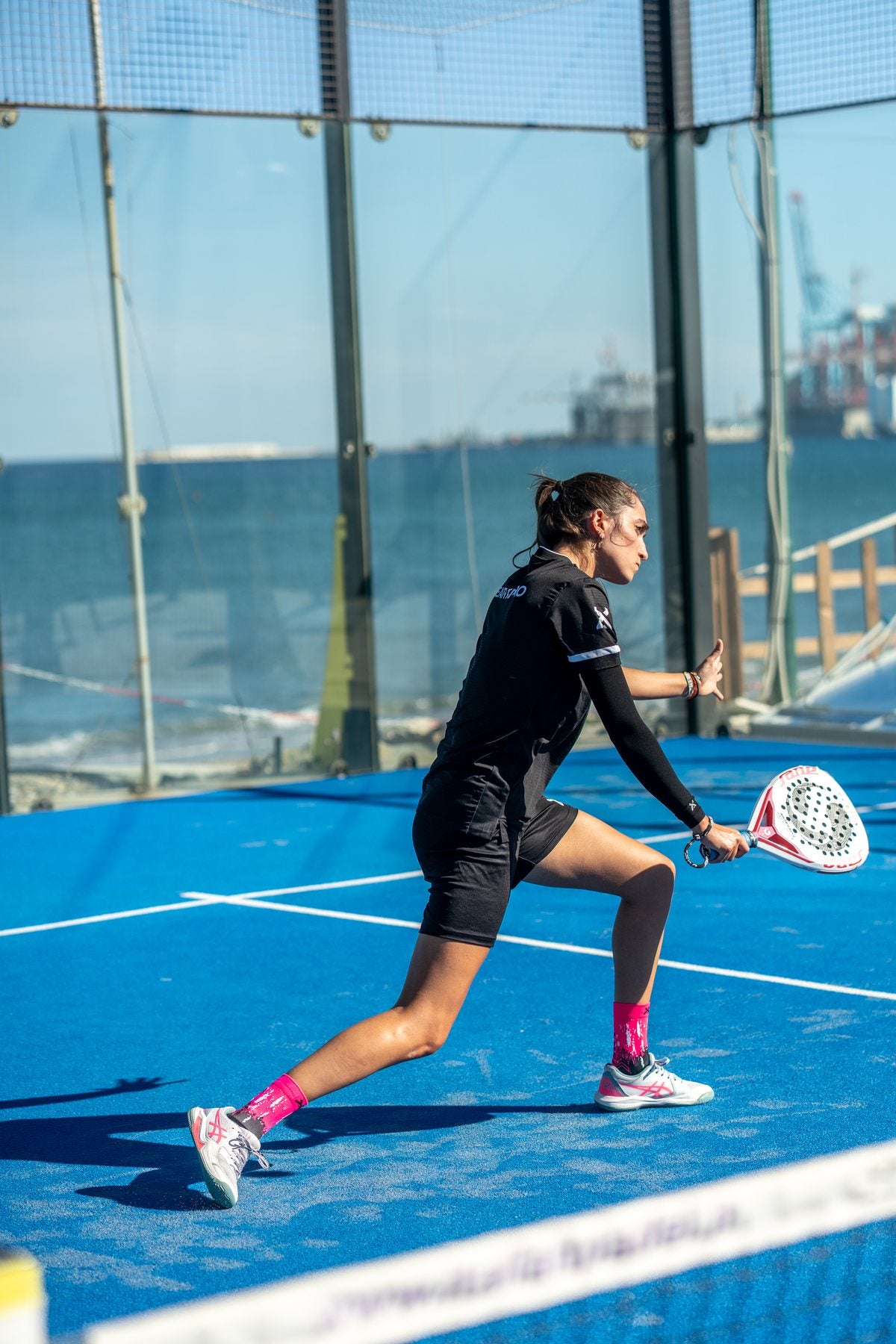 Padel-Spielerin in der Defensive mit schwarzer Arm Sleeve